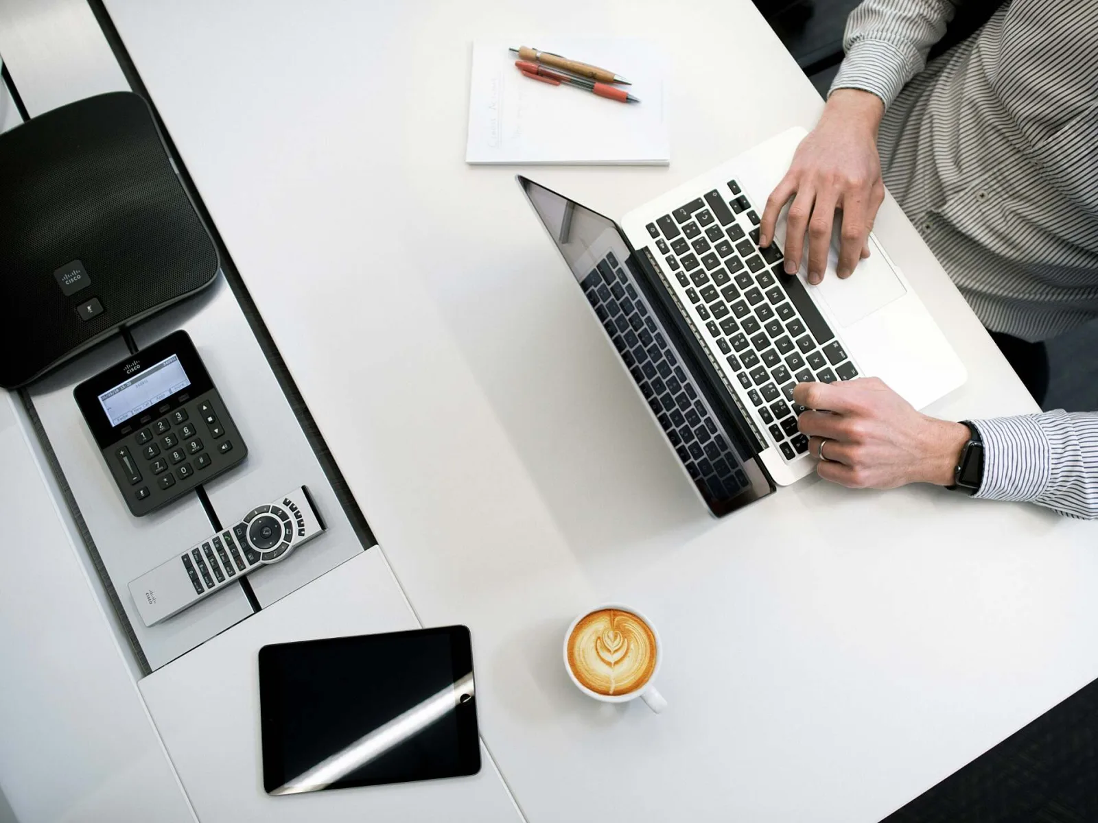 Een overzichtelijke werkplek met laptop, notitieboek en koffie